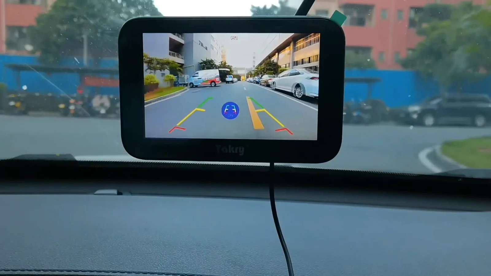A five-inch monitor on a dash with the road behind the vehicle on it
