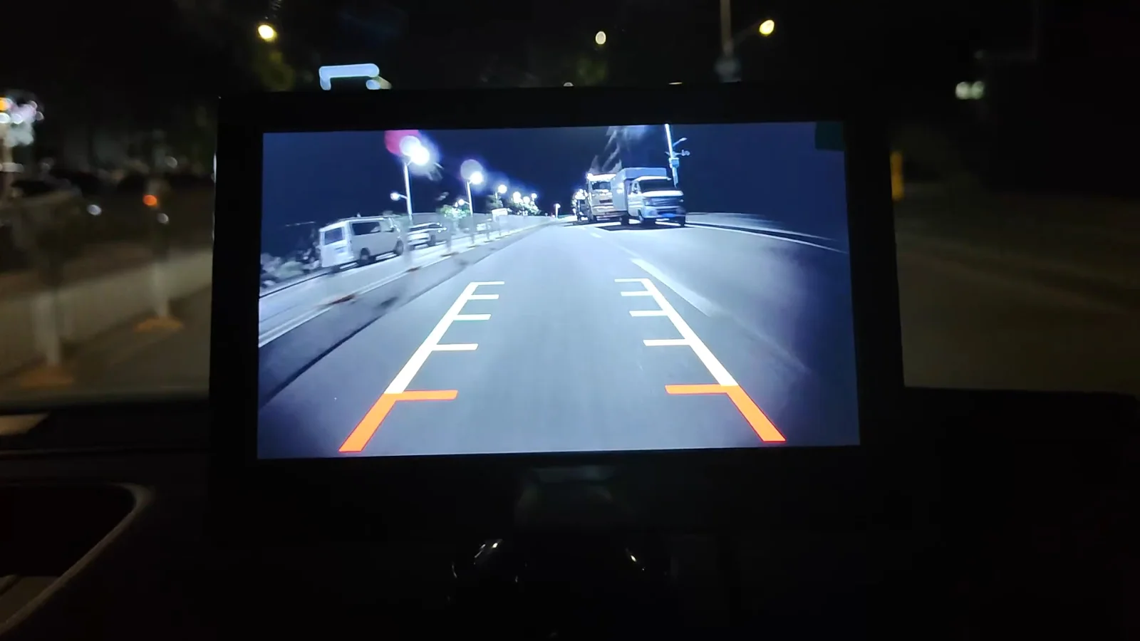A reversing picture with guide lines on a dash monitor at dusk